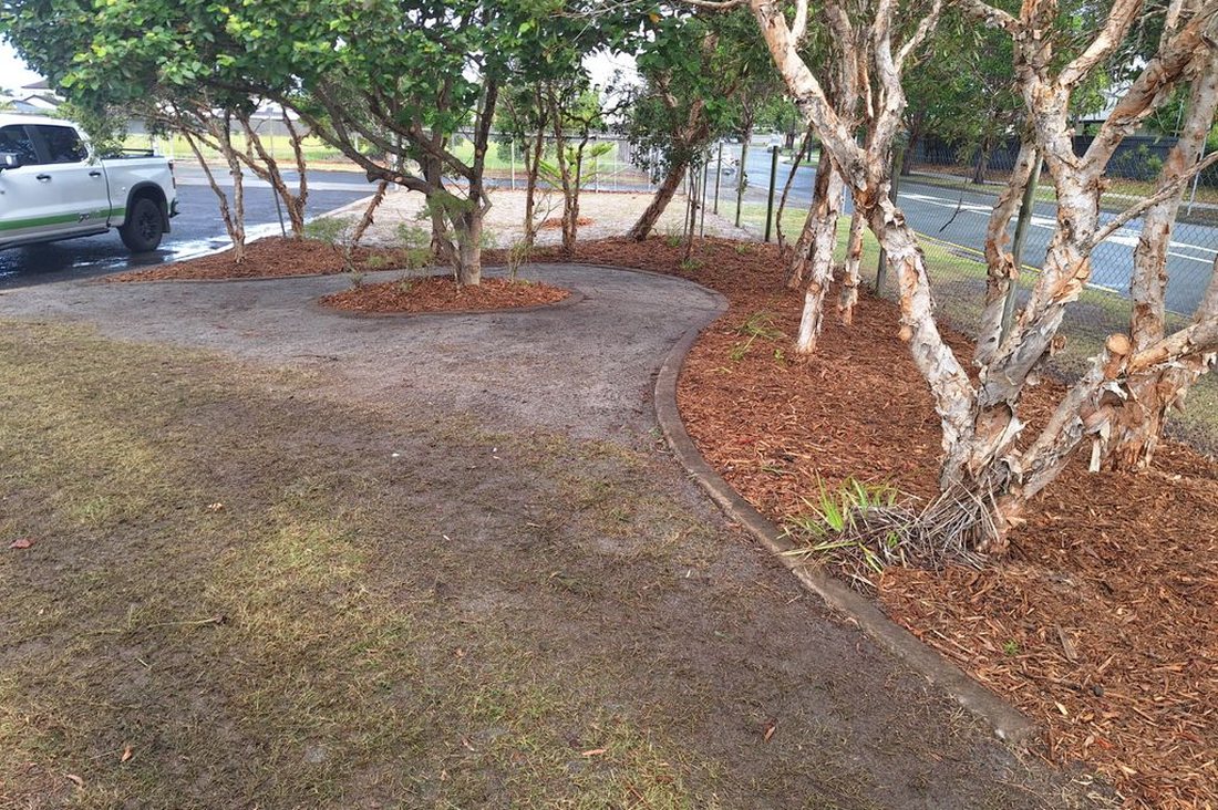 Bokarina Beach Village — curved garden bed with lomandra grasses and mature trees